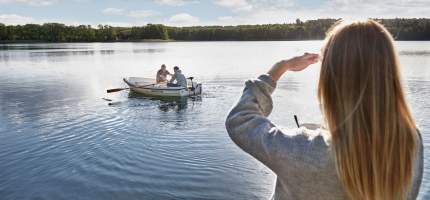VRK bAV – Eine Frau beobachtet ihren Mann, der auf einem See mit seinem Vater Boot fährt.