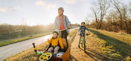 VRK Fahrradversicherung – Eine junge Frau fährt mit Ihren kleinen Kindern Fahrrad.