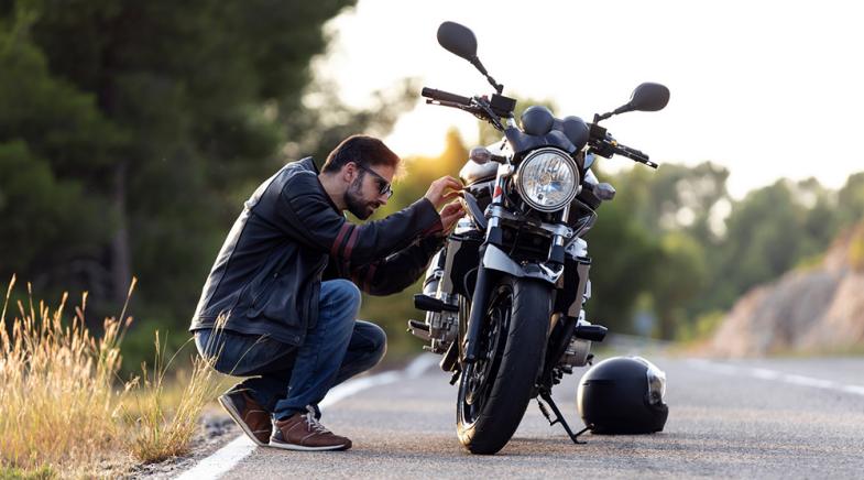 VRK Motoradversicherung – Ein junger Mann steht mit seinem Motorrad auf einem Feldweg.