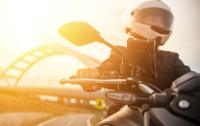 VRK Motorradversicherung – Eine Frau fährt bei Sonnenuntergang auf einem Motorrad