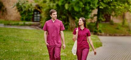 Versicherung für Pflegepersonal – Zwei Pflegekräfte laufen auf einem Weg.