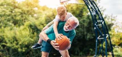 VRK Seniorenunfallversicherung – Ein Senior spielt mit seinem Enkel Basketball.