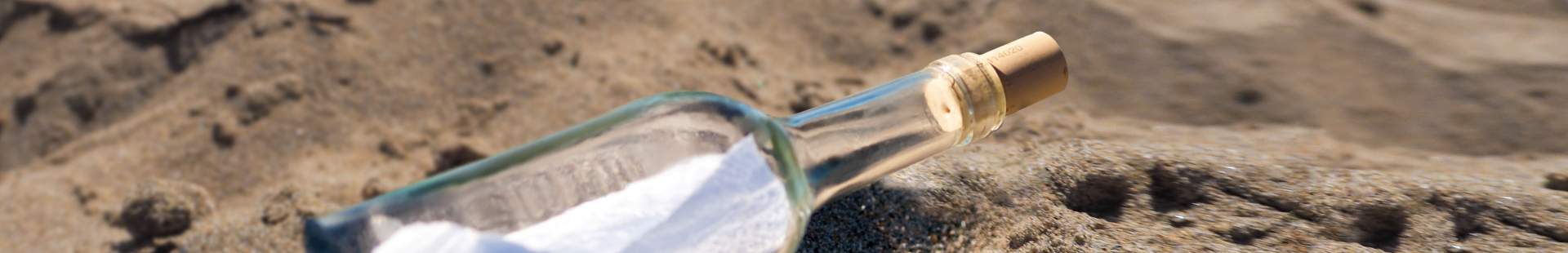 VRK Änderungsmitteilung – Eine angespülte Flaschenpost am Strand im Sand.