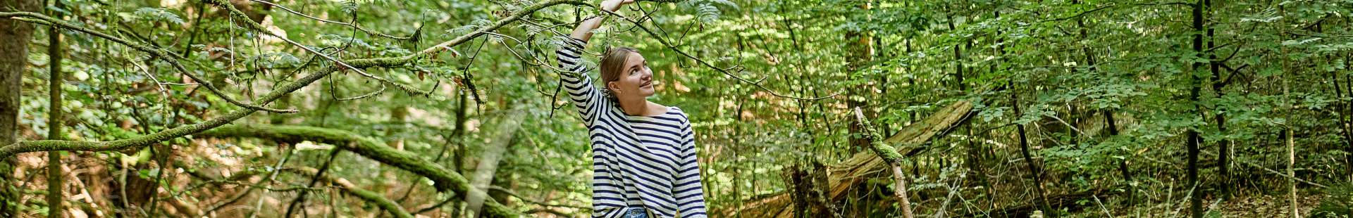 VRK – Nachhaltige Gütesiegel im Blick – Eine junge Frau geht durch den Wald spazieren.