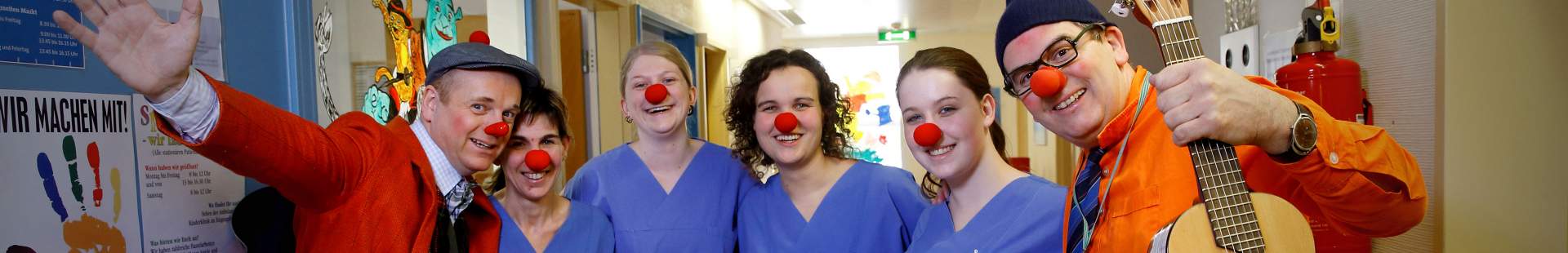VRK Projekt Freude pflegen – Zwei HHH Clowns stehen mit Pflegekräften, die rote Clownsnasen auf haben, in einer Einrichtung.