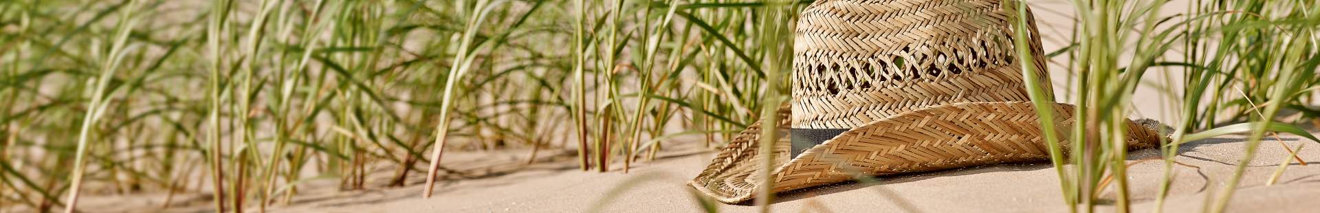 VRK Reiserücktritt – Ein Strohhut der in den Dünen am Strand liegt.