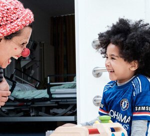 VRK HUMOR HILFT HEILEN – Zwei HHH Clowns spielen mit einem Kind auf dem Boden in der Asklepios Kinderklinik.