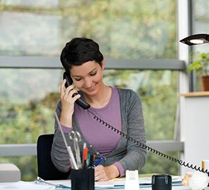 Karriere im Innendienst – Eine junge Frau, die ein Telefonat an ihrem Arbeitsplatz führt.