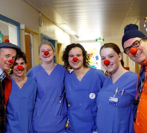 VRK Projekt Freude pflegen – Zwei HHH Clowns stehen mit Pflegekräften, die rote Clownsnasen auf haben, in einer Einrichtung.