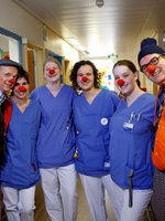 Zwei HHH Clowns stehen mit Pflegekräften, die rote Clownsnasen auf haben, in einer Einrichtung.