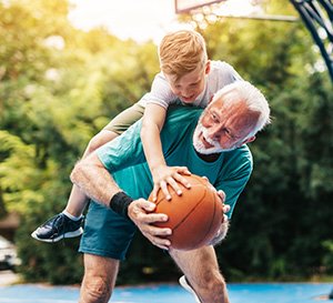 VRK Seniorenunfallversicherung – Ein Senior spielt mit seinem Enkel Basketball.