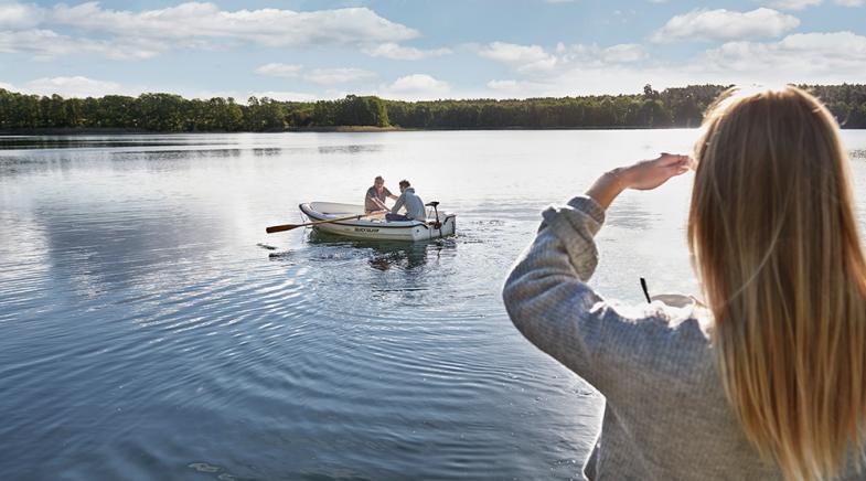 VRK bAV – Eine Frau beobachtet ihren Mann, der auf einem See mit seinem Vater Boot fährt.