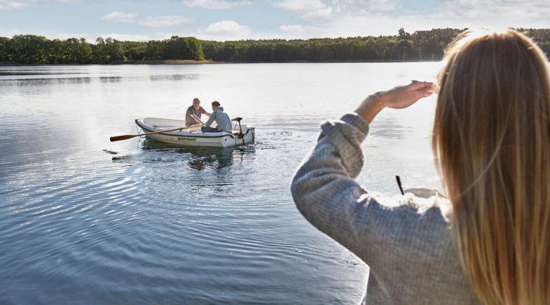 VRK bAV – Eine Frau beobachtet ihren Mann, der auf einem See mit seinem Vater Boot fährt.