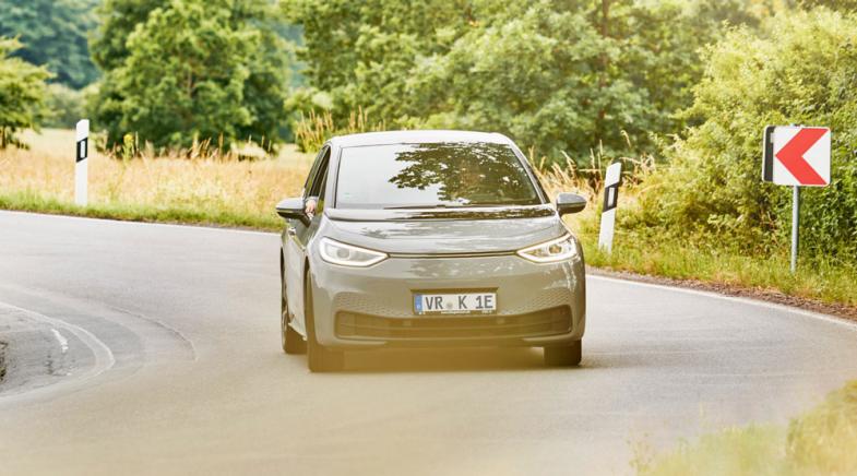 VRK Elektroautoversicherung –  Ein E-Auto fährt auf einer Landstraße durch eine Kurve.