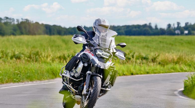 VRK Motoradversicherung – Ein junger Mann steht mit seinem Motorrad auf einem Feldweg.