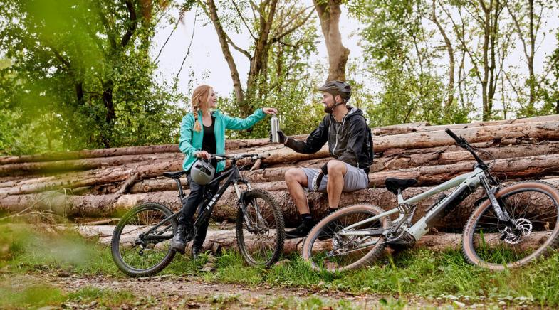 VRK Pdelec-Versicherung – Ein junges Paar fährt mit E-Bikes durch die Natur.