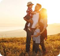 Arbeit und Familie – Eine junge Familie steht auf einem Feld.