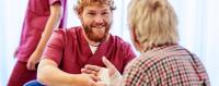 Pflegeversicherung Ein männlicher Pfleger verbindet einen Patienten