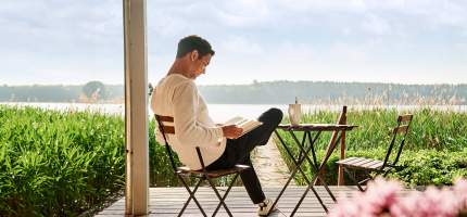 VRK Privat-, Berufs- & Verkehrsrechtsschutz – Ein junger Mann sitzt auf seiner Terrasse und liest ein Buch.