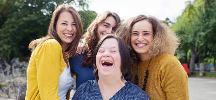 VRK Unfall­versicherung für Menschen mit geistiger Behinderung – © Foto: Conny Wenk – Eine junge Frau mit Down-Syndrom lacht mit ihren Freundinnen.
