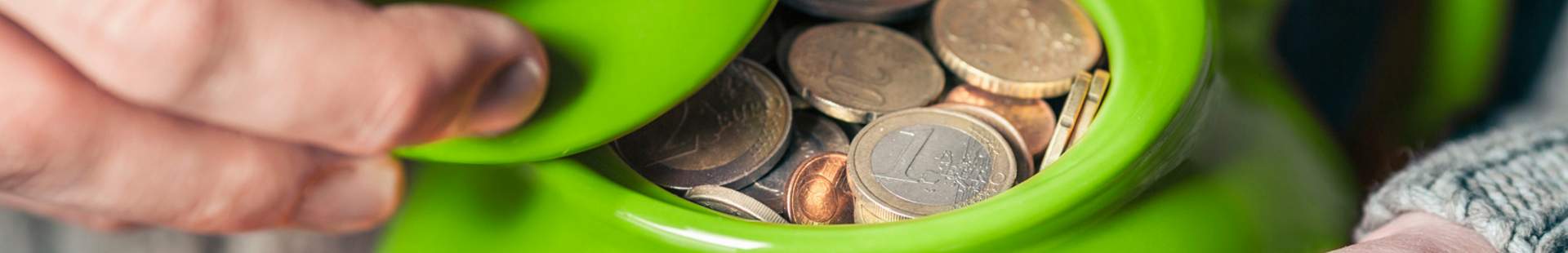 VRK Pflege-Monatsgeldversicherung – Eine grüne Teekanne mit Geld, die in zwei Händen gehalten wird.