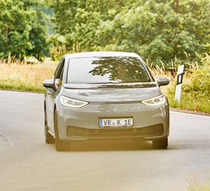 VRK Elektroautoversicherung –  Ein E-Auto fährt auf einer Landstraße durch eine Kurve.