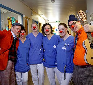 VRK Projekt Freude pflegen – Zwei HHH Clowns stehen mit Pflegekräften, die rote Clownsnasen auf haben, in einer Einrichtung.